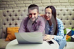 Couple sitting on couch and looking at laptop