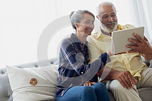 Couple sitting on couch while using a tablet