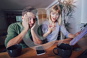 Couple sitting at the desk at home read notice paper check bills or bank account