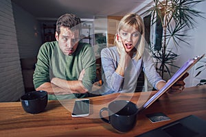 Couple sitting at the desk at home read notice paper check bills or bank account