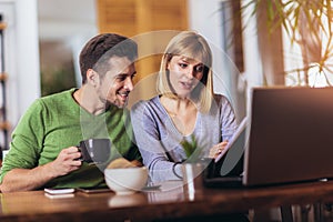 Couple sitting at the desk at home read notice paper check bills or bank account balance