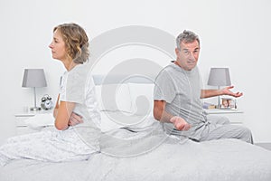 Couple sitting on different sides of bed having a dispute