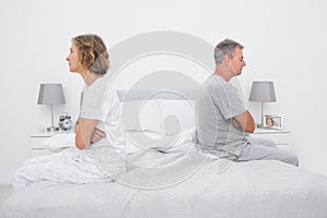 Couple sitting on different sides of bed not talking after dispute