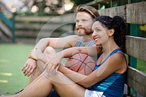 couple sitting down on outdoor basketball court