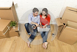 couple sitting on floor moving in new house choosing furniture with computer laptop