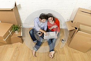 couple sitting on floor moving in new house choosing furniture with computer laptop