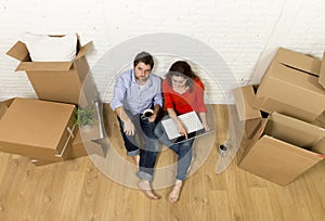 couple sitting on floor moving in new house choosing furniture with computer laptop
