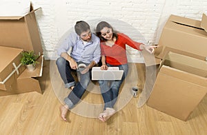 couple sitting on floor moving in new house choosing furniture with computer laptop