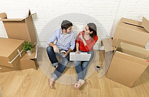 couple sitting on floor moving in new house choosing furniture with computer laptop