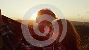 Couple sitting in grassy field at sunset. Hikers resting after hike in mountains