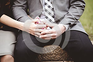 Couple sitting while holding hands together and praying beside a grassy lawn