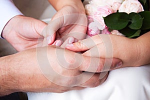 couple sitting holding hands with woman& x27;s hand on top of man& x27;s hand