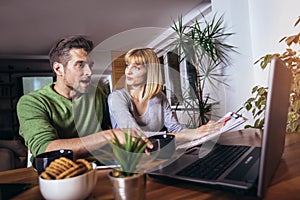 Couple sitting at home read notice paper check bills or bank account balance