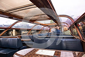 Couple sitting on interior seating inside a glass roofed sightseeing canal cruise trip boat for tourists