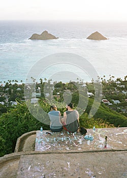 Couple sitting at Lanikai Pillbox with the view of the Mokulua islands in the background