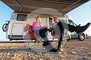 Couple sitting near camper resting drinking coffee