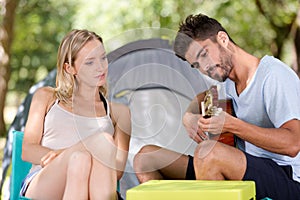 couple sitting near tent with guitar