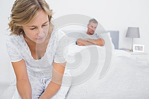 Couple sitting on opposite ends of bed after a fight