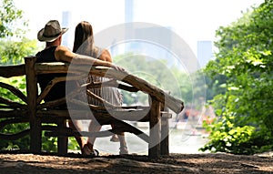 Couple sitting on a park bench and having a romantic first date. Lovers with romance and trust.