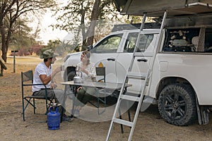 couple sitting in portable chairs drinking tea talking. camping summer activities