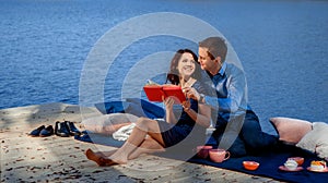 Couple sitting and reading on terrace near the water