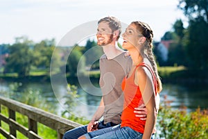 Couple sitting at riverbank in summer
