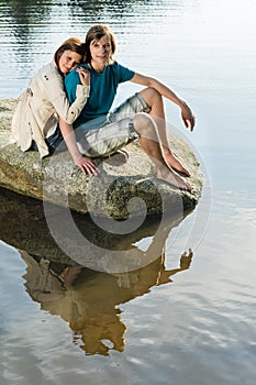 Couple sitting on rock sunset by lake