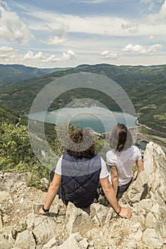 Couple sitting at rocks at mountain viewpoint