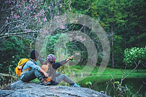 Couple sitting on rocks and taking pictures nature, flowers. at Paphiopedilum orchid conservation center