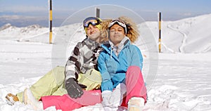 Couple sitting in snow on ski slope