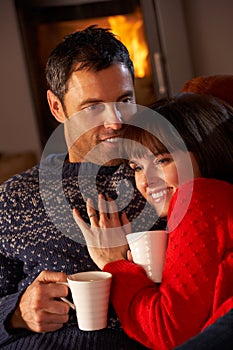 Couple Sitting On Sofa By Cosy Log Fire