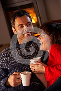 Couple Sitting On Sofa By Cosy Log Fire