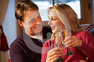Couple Sitting On Sofa With Glasses Of Champagne