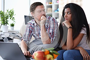 Couple sitting sofa at home looking at each other