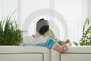 Couple sitting on sofa hugging back view