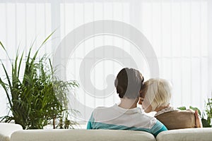 Couple sitting on sofa hugging back view