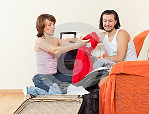 Couple sitting on sofa and packing suitcase at home