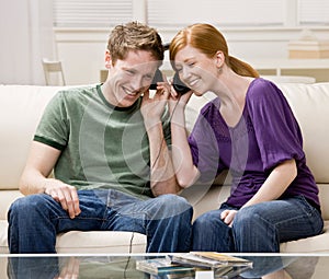 Couple sitting on sofa and sharing headphones