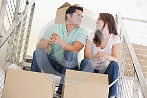 Couple sitting on staircase with boxes in new home