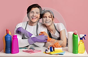 Couple Sitting At Table With Lots Of Detergents And Cleaning Supplies