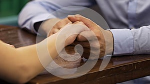 Couple sitting at table, male taking woman by hand, romantic date, confession