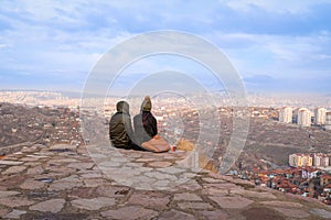 Couple sitting on the top of Ankara Castle and watching slum houses around castle
