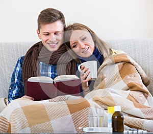 Couple sitting under blanket with book