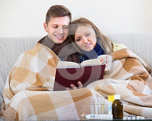 Couple sitting under blanket with book