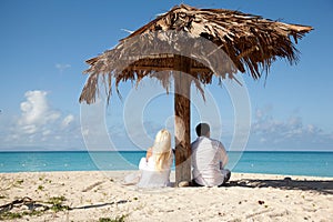 Couple sitting under palm umbrella