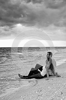 Couple sitting in water at the beachin black and w