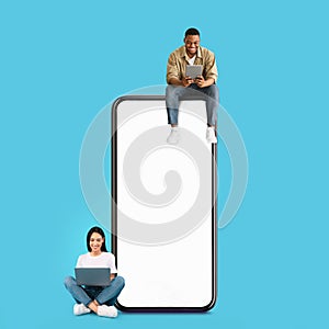 Couple sitting on white empty smartphone screen and using gadgets