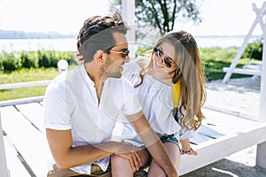 couple sitting on wooden bench at city beach and looking