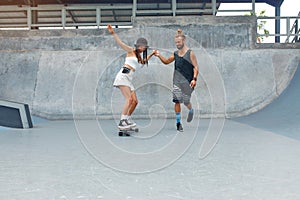 Couple At Skatepark. Happy Guy And Girl In Casual Outfit Riding On Skateboard