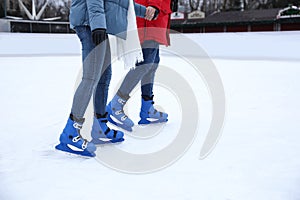 Couple skating along ice rink outdoors, closeup